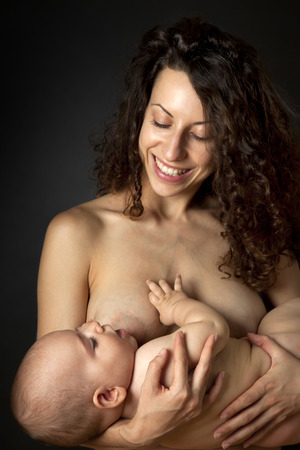Mother breastfeeding her baby. Studio shot. Black background.の写真素材