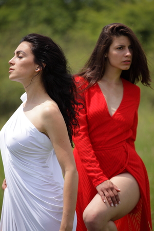 Portrait of two sexy women in nature with red and white dresses.の写真素材