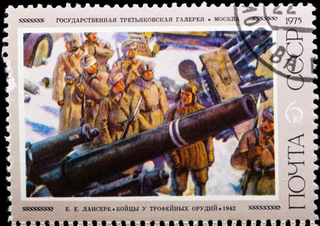 Postal stamp. Military people in winter clothes near to the weapon.