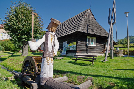 Wooden sculpture of herdsman - probably famous bandit Juraj Janosik who was born in this village - in the front of an old wooden house in Terchova village, northwest Slovakiaの写真素材
