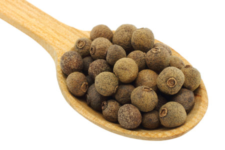 Seeds of allspice in wooden spoon on white background 