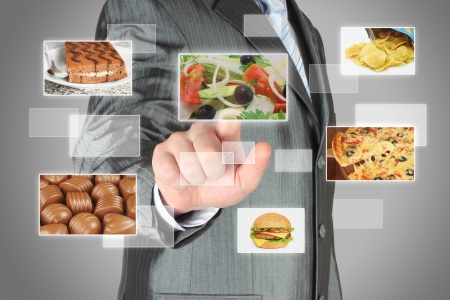 Businessman pushes touch screen button with salad on virtual interface with food  Diet conceptの写真素材