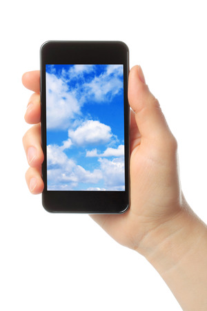 Woman hand holds smart phone with sky on white background, cloud computing concept の写真素材