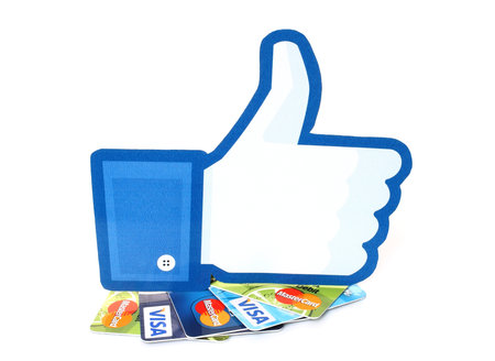KIEV, UKRAINE - MARCH 21, 2015: Facebook thumbs up sign printed on paper and placed on cards Visa...