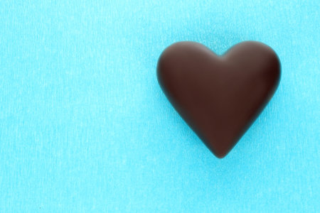 Black chocolate heart on blue background close-upの写真素材