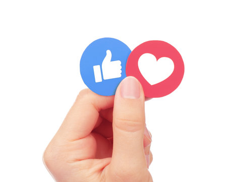 Kiev, Ukraine - September 04, 2017: Hand holds Facebook Like and Love Empathetic Emoji Reactions,...