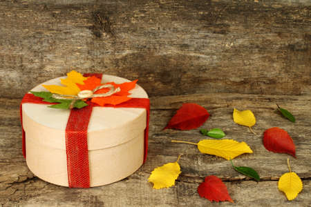 Autumn concept of present box with dried leaves on wooden backroundの写真素材