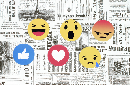 Kiev, Ukraine - February 08, 2018: Facebook like button 6 Empathetic Emoji Reactions printed on paper and placed on retro newspaper background. Facebook is a well-known social networking serviceのeditorial素材