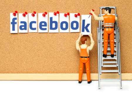 Kiev, Ukraine - November 27, 2019: Two toy men pin letters of Facebook word on cork board. Facebook is a well-known social networking serviceのeditorial素材