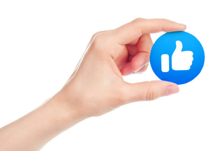 Kiev, Ukraine - May 15, 2019: Hand holds New Facebook Like icon printed on paper. Facebook is a well-known social networking serviceのeditorial素材