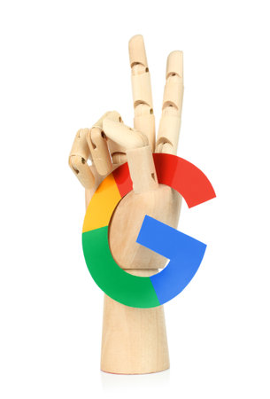 Kiev, Ukraine - May 04, 2022: Wooden hand holds Google paper logo and show victory gesture, on white background.のeditorial素材