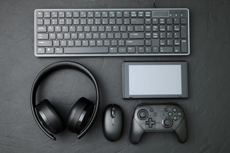 Black devices: gamepad, computer mouse, keyboard, headset and tablet pc. Gaming concept on black...