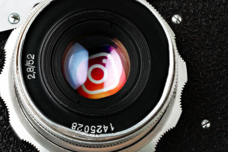 Retro photo camera lens with Instagram app icon in it close-up. Instagram is an American photo and video sharing social networking service owned by Meta Platformsのeditorial素材