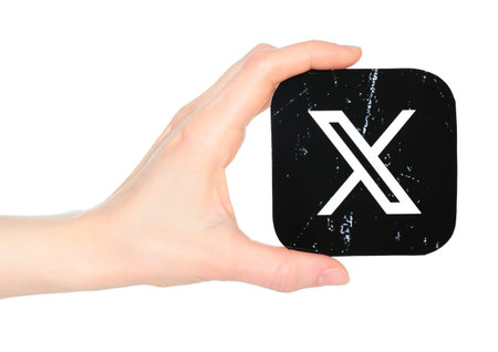 Hand holds paper X - Twitter mobile app icon, on a transparent background. Popular social media...