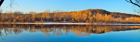 Spring landscape is reflected in the calm water of the river. Nature wakes up 