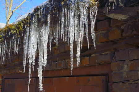 Icicles hanging on roof dripping close up. Beautiful element of winter or spring designの写真素材