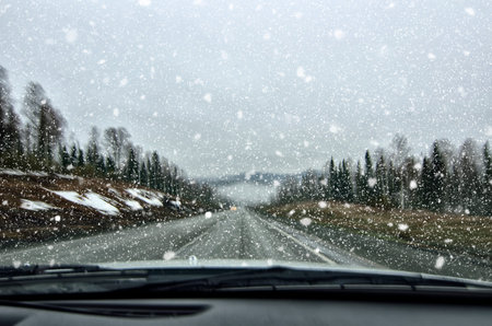 Vehicle safety in winter. Car driving in dangerous winter weather with poor visibility during snowfall and mist on the highway, concept for safety in traffic, copy space. Blurred view in car windshield の写真素材
