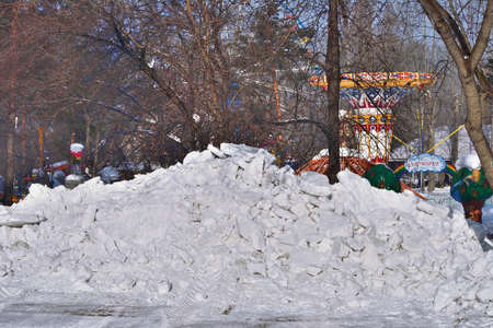 Snowdrift in the city park. Municipal communal services are cleaning snow on roads and alleys of city park. High snowdrift after snowfall or blizzard in snowy siberian winterの写真素材