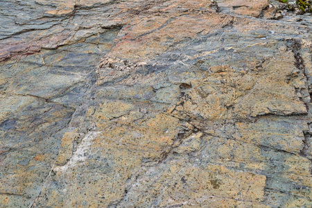Weathered mountain rock texture - colorful stone background. Grunge wallpaper - surface of ancient...