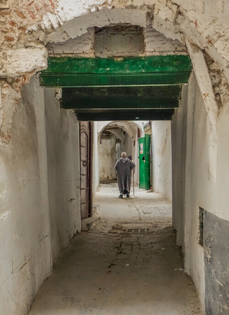 Passage in the medina of Tetuan, with an old man on his back walking in the passageのeditorial素材