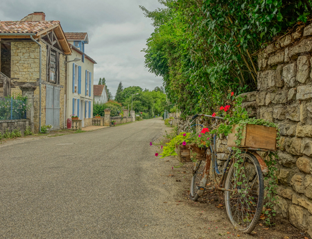 Side view of an old bicycle decorated with flowers at the beginning of a village streetのeditorial素材