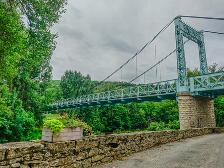 Old iron suspension bridge in natural surroundings on a cloudy autumn dayのeditorial素材