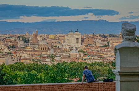 View of a sunset in Rome from a terrace with a person on his backのeditorial素材
