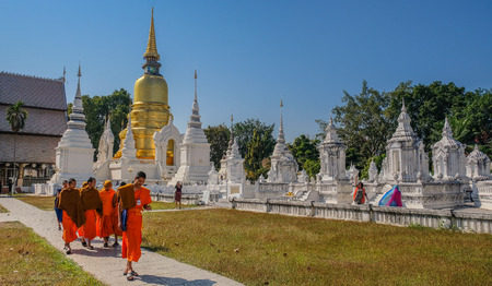 Group of Buddhist monks walking through a white temple with people visitingのeditorial素材
