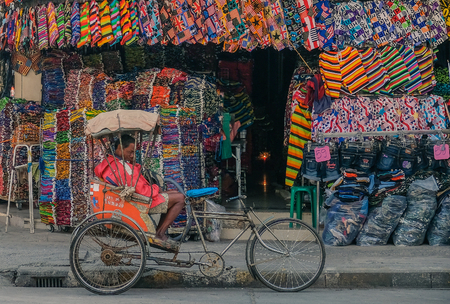 Udon Thani, Thailand - February 4, 2018: Man driver sitting in bicycle taxi in front of colorful clothing storeのeditorial素材