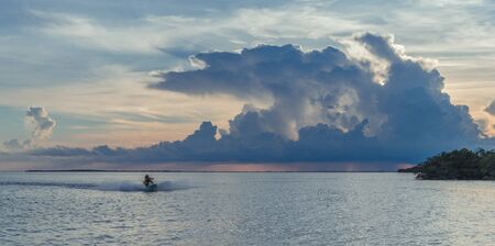 Overseas highway to Key West island, Florida Keys, Florida, USA - July 15, 2018: Jet ski on the horizon of the Florida Keys at a sunset with storm cloudsのeditorial素材