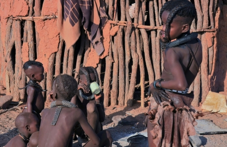 EPUPA, KAOKOLAND/NAMIBIA - OCTOBER 16: Himba youngsters talk and drink on October 16, 2010 in a seasonal hamlet near Epupa, Kunene-Kaokoland-Namibia. Names-Ages (l.-r.): Umuniangwe-4, Mukakamunwe-3, Menjamwapi-11, Twakoseka-10, Uvaserwa-11. のeditorial素材