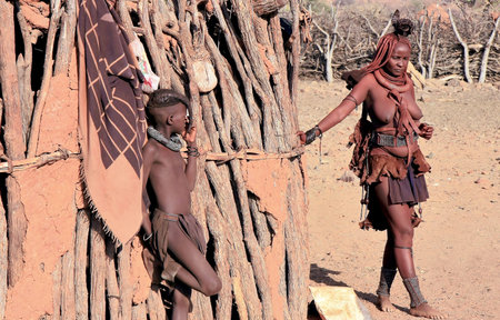 EPUPA, KAOKOLAND/NAMIBIA - OCTOBER 16: Himba woman quits her hut-her daughter looking on October...
