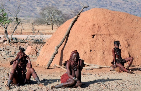 EPUPA, KAOKOLAND/NAMIBIA - OCTOBER 16: Himba women and girl sit down on the floor on October 16, 2010 in a seasonal hamlet near Epupa, Kunene-Kaokoland-Namibia. Girl's name-age: Katjambia-11.のeditorial素材