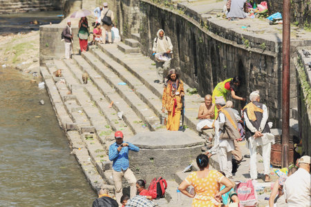 DEOPATAN, KATHMANDU, NEPAL - OCTOBER 5  Bhatta priests and hindu sadhus attend nepali faithfuls who offer them food as present on the ghats of the Bagmati river on October 5, 2012 in Pashupatinath temple-Deopatan-Kathmandu-Nepal のeditorial素材