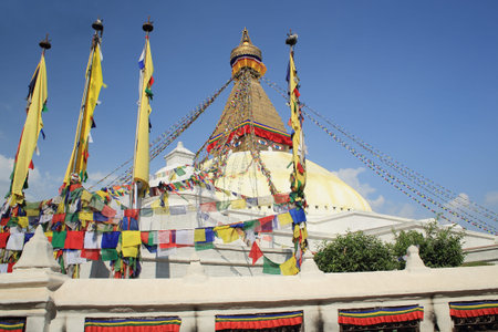 The white big stupa of Boudhanath-Bodhnath with many colored buddhist prayer flags hanging from its golden 13 storey tower-the eyes of the Buddha looking towards the 4 cardinal points-sorrounded by prayer wheels  Kathmandu-Nepal の写真素材
