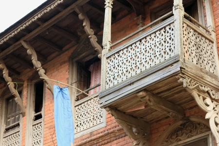 Old red brick house in the traditional newari style with carved wood balcony-windows-parapets-roof beams in the central street of Bandipur town-Tanahu District-Gandaki Zone-Nepal.のeditorial素材