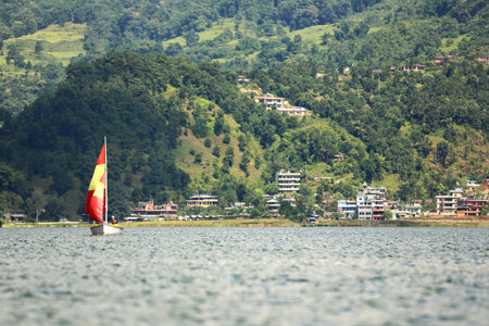 POKHARA, NEPAL - OCTOBER 12: Tourist women sail the waters of lake Phewa on a racing sailboat with red and yellow sails on october 12, 2012 in Pokhara-Kaski district-Gandaki zone-Nepal.のeditorial素材