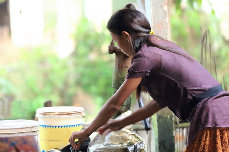 PATIHANI, NEPAL - OCTOBER 13: Young woman of the tharu people collects and packs her wash in a bamboo and reef shed on October 13, 2012 in Patihani-Chitwan distr.-Narayani zone-Nepal.のeditorial素材