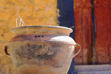 Big terracotta plantpot at the entrance of a yellow paintedred door building. Way down from the main...