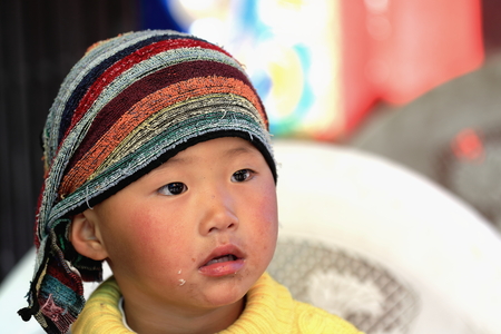 SHIGATSE, TIBET, CHINA-OCTOBER 24: Kid with towel on head waits for his parents to end shopping-market around Tashilhunpo-Heap of Glory monast.-seat of Panchen Lama on October 24, 2012. Shigatse-Tibet.のeditorial素材