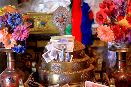 Dharmachakra topped brass mandala set-plastic flowers-metallic vases-money offerings. Shrine on Ponpori Hill-right bank of Trum or Chong Chu river-grounds of Sakya-Grey Soil monast.North Seat. Tibet.の写真素材