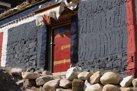 Grey-red-white painted house with red door. Grounds of the 1073 AD-Khon Konchog founded North Seat of Sakya-Grey Soil monast. Slope of Ponpori Hill-right bank of Trum or Chong Chu-river. Sakya-Tibet.の写真素材