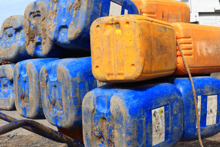 Big blue-yellow plastic jerrycans-empty and piled on an iron wheelbarrow placed on the main-unique...