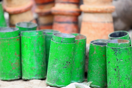 Green painted metal cylinders placed before a set of unidentified clay pottery-counter of a shop in the Adi Haki open market of Mek'ele-Mekelle town in Debubawi-Southern zone. Tigray region-Ethiopia.の写真素材