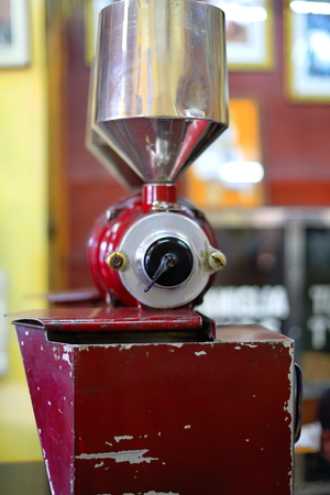 Red painted old italian style vintage coffee grinder along with metal box containing roasted coffee beans ready to be ground in the Tomoca Coffee Shop of the Piazza-downtown area. Addis Ababa-Ethiopiaの写真素材