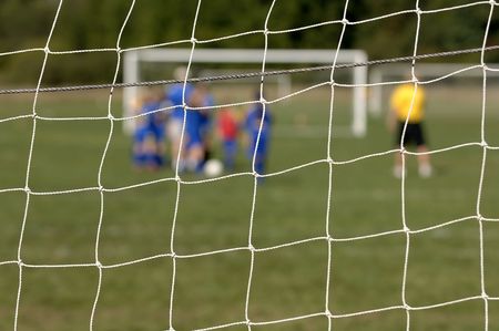 Soccer team out of focus behind the goalie netの写真素材