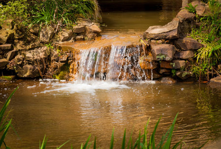 Water cascades over a man made waterfall with tectured rocks and stone.の写真素材