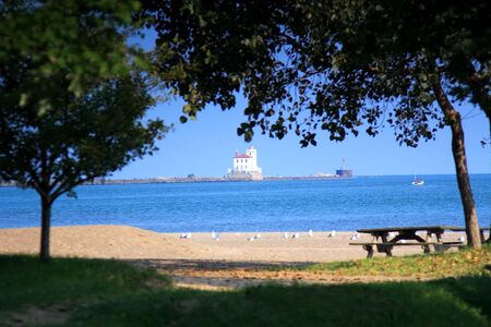 Scene with picnic area and beach in foreground and Fairport Harbor Lighthouse in the backgroundの写真素材