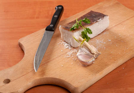 Sliced lard on wooden table with onion and knife horizontal. Fresh, rural, homemade products on wooden tableの写真素材