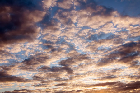 Cumulus sunset clouds with sun setting down. Summer evening sky and clouds